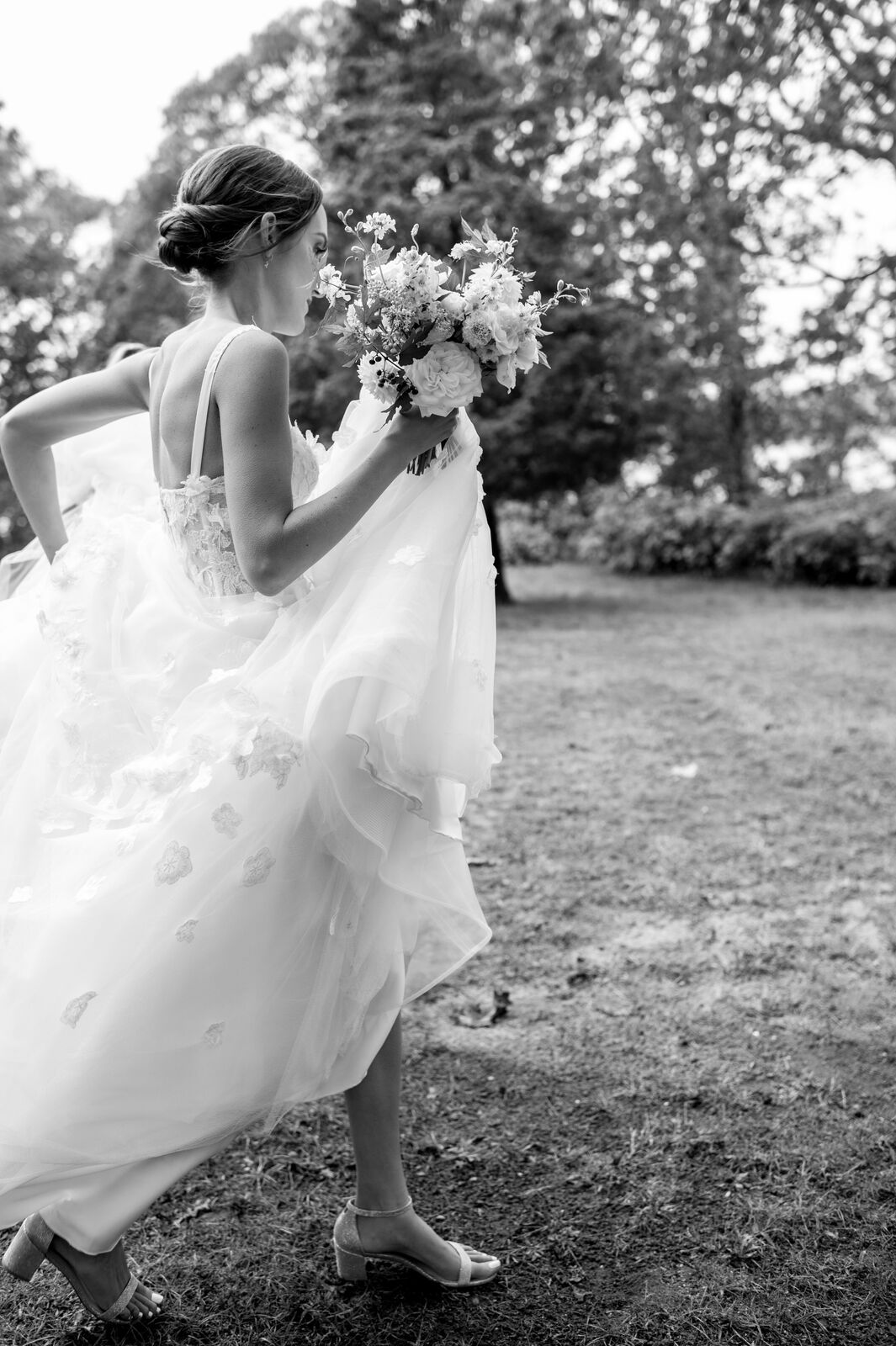 Bride walking through a field, dress flowing, black and white
