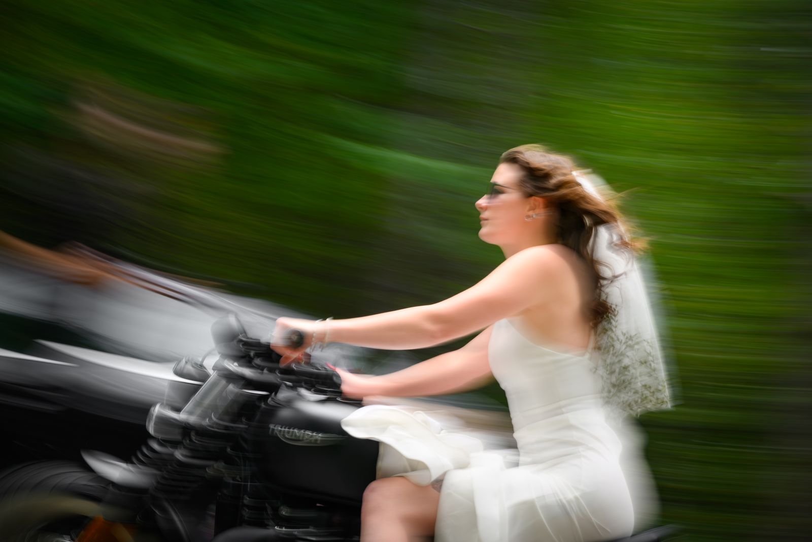 Bride riding a motorcycle in her wedding dress and veil on the way to Cathedral Ledge