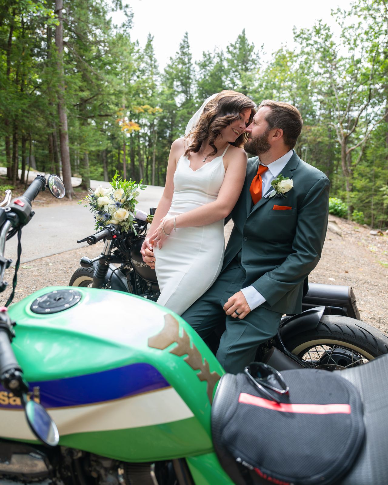 Groom seated on his green motorcycle kissing the bride after their Echo Lake wedding
