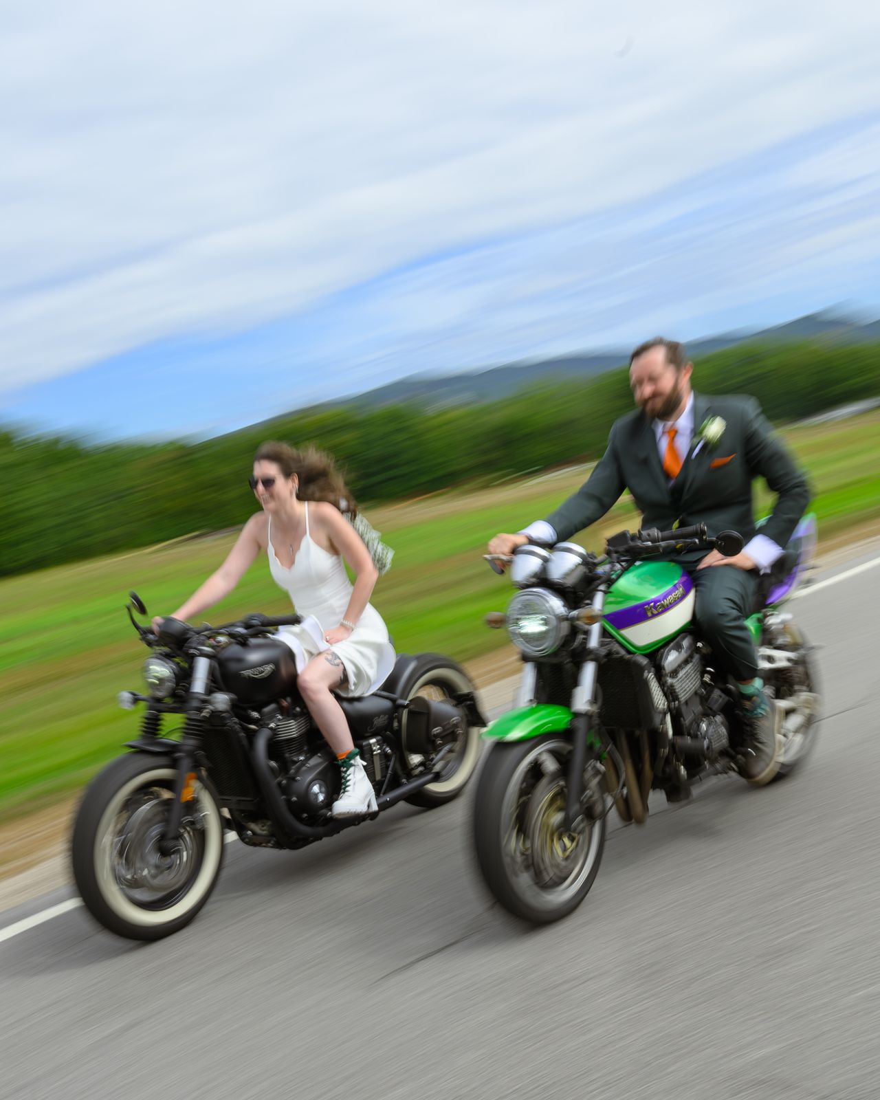 Bride and groom riding their motorcycles together on a mountain road in New Hampshire, blurred with speed