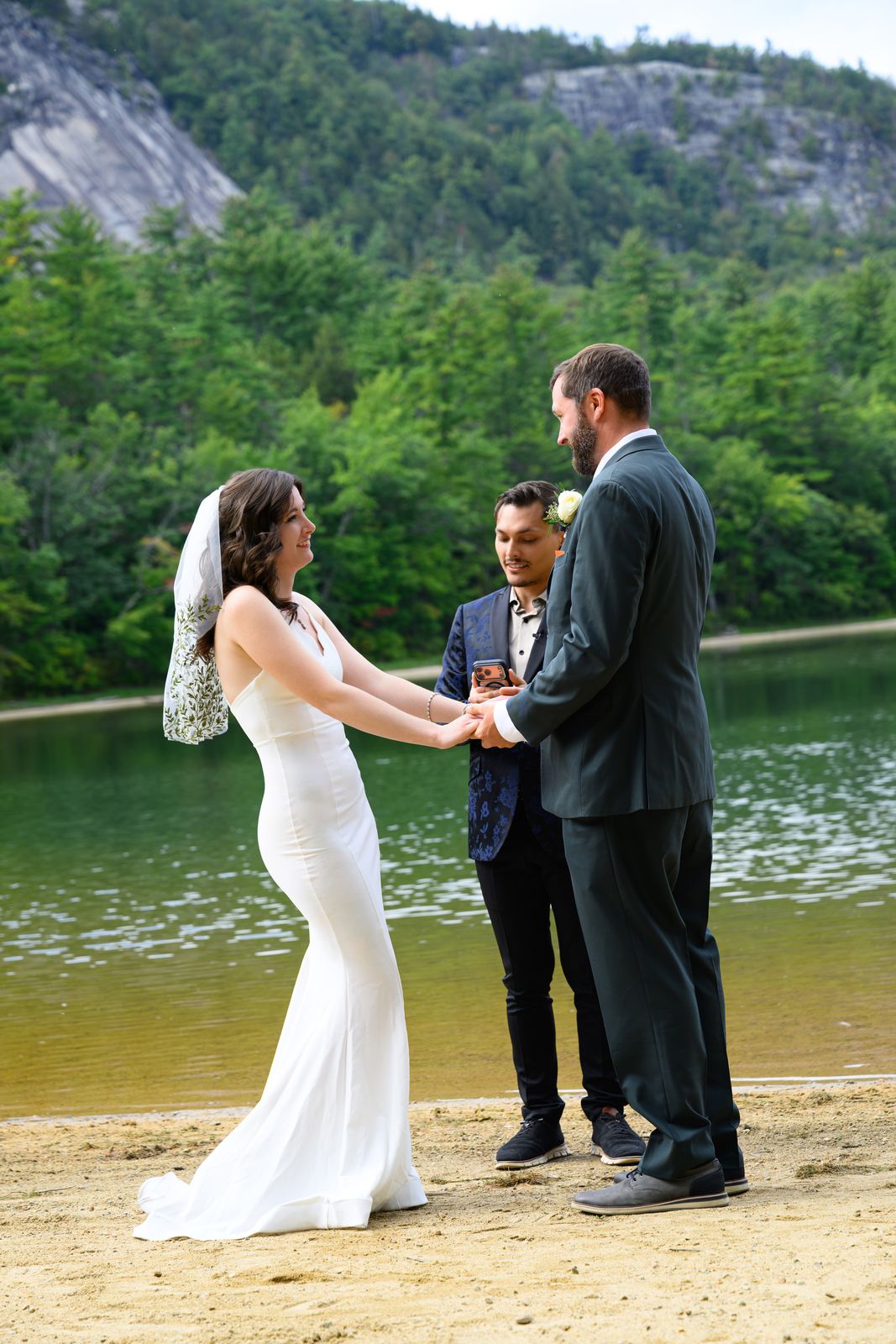 Bride and groom holding hands with their officiant during an Echo Lake State Park ceremony