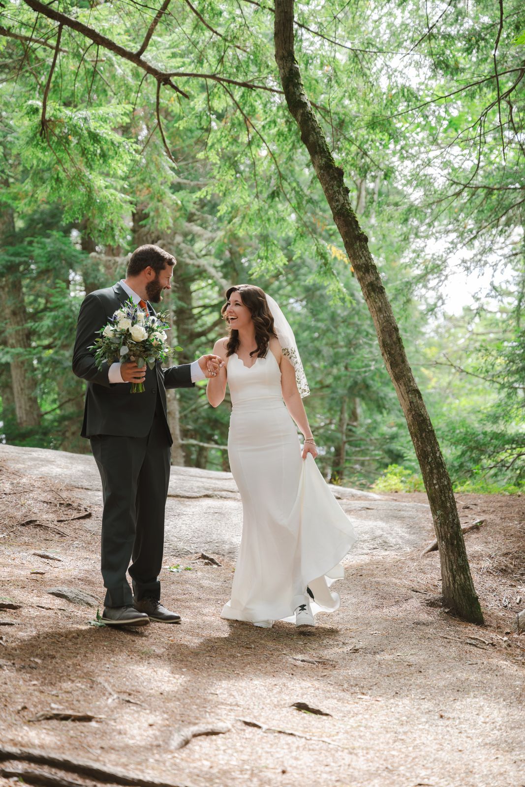 Bride and groom laughing during their first look among the pine trees at Cathedral Ledge