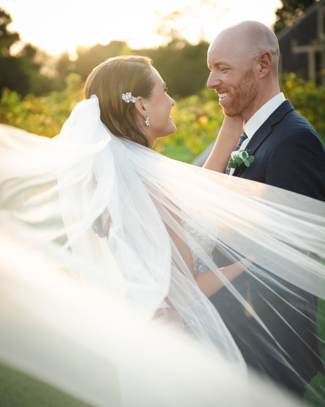 Couple kissing at sunset as the veil catches the wind